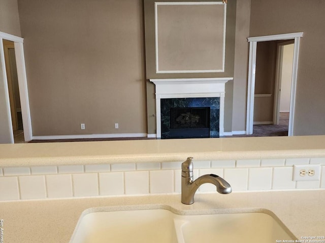 interior details featuring baseboards, light countertops, a sink, and a fireplace