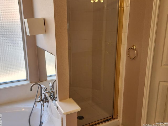 bathroom featuring a textured wall, a stall shower, and a garden tub