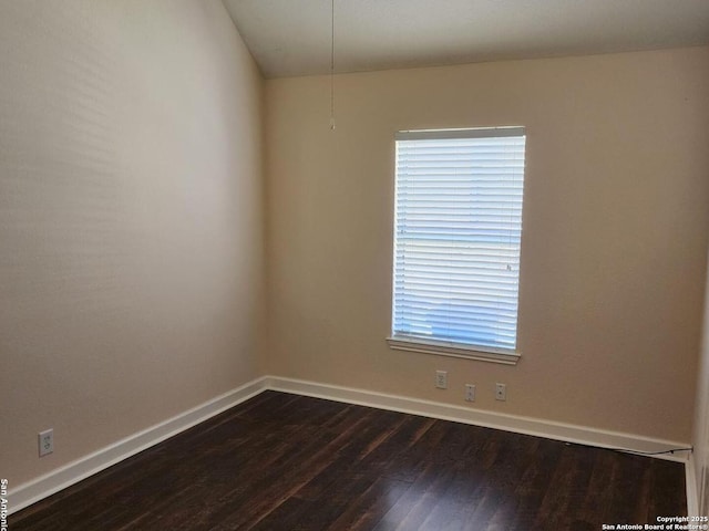 spare room featuring dark wood-style flooring and baseboards