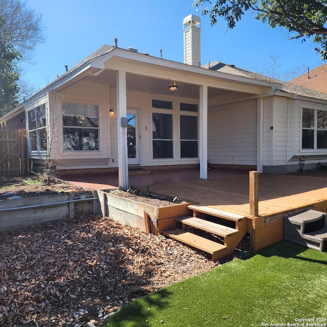 back of property with a deck, fence, and a chimney