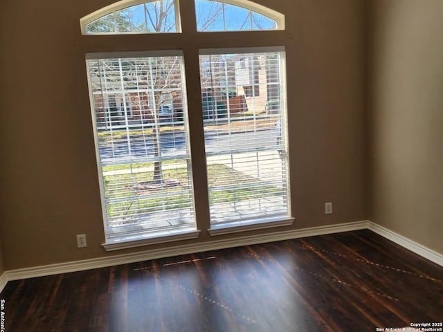 spare room with baseboards and wood finished floors