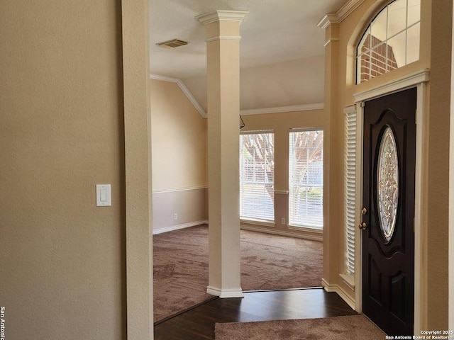 foyer with dark wood-style flooring, visible vents, baseboards, decorative columns, and crown molding