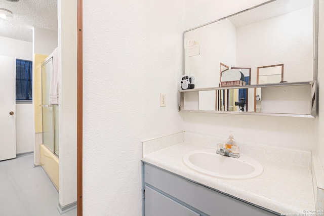 full bath with combined bath / shower with glass door, a textured ceiling, and vanity