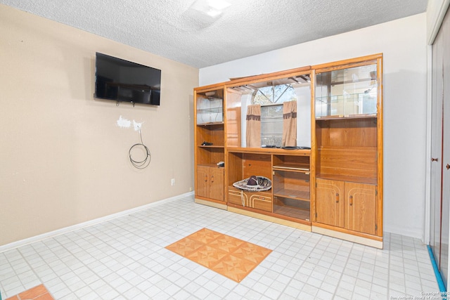 interior space featuring a textured ceiling and baseboards