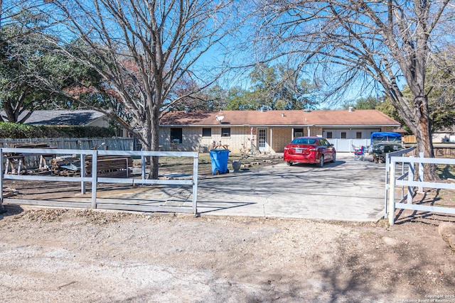 view of front facade featuring driveway, brick siding, and fence