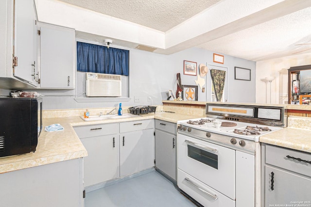 kitchen with light countertops, white range with gas cooktop, a textured ceiling, and a peninsula