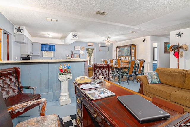 living area featuring ceiling fan, visible vents, a textured ceiling, and a wall mounted AC