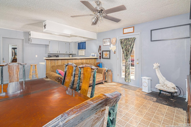 dining space with baseboards, a ceiling fan, and a textured ceiling