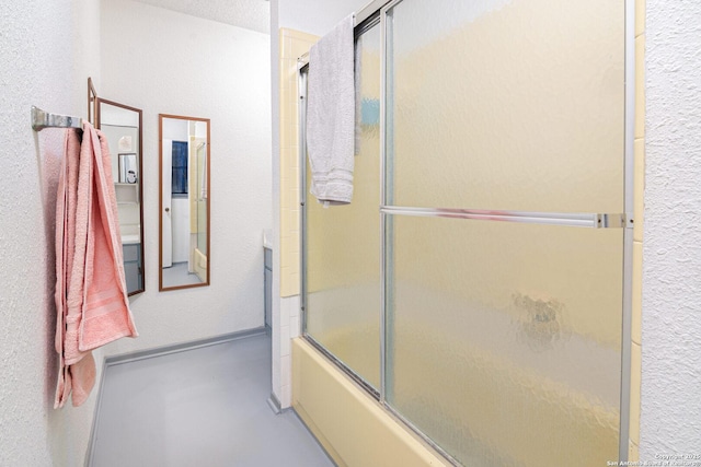 full bath featuring a textured wall and bath / shower combo with glass door