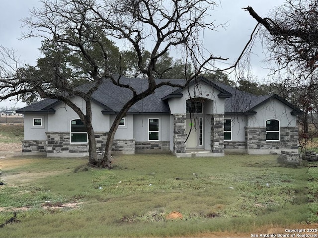 view of front of property featuring stone siding, a shingled roof, and stucco siding