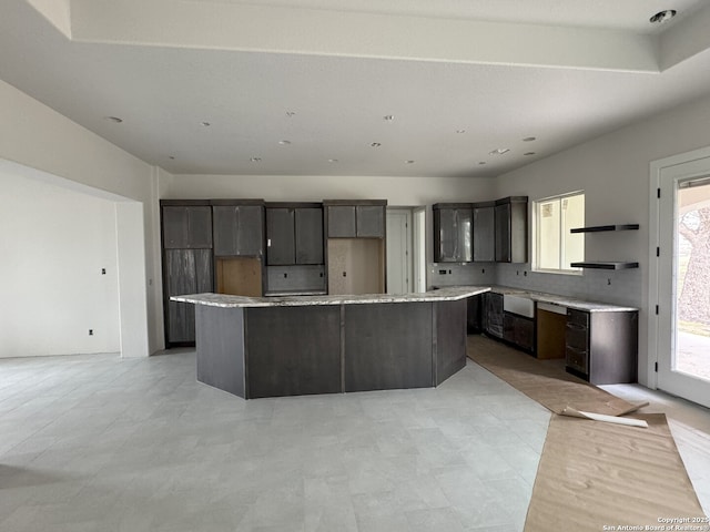 kitchen with light countertops, a kitchen island, open shelves, and modern cabinets