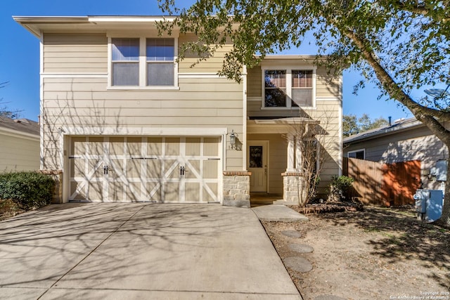 view of front facade with driveway, an attached garage, and fence