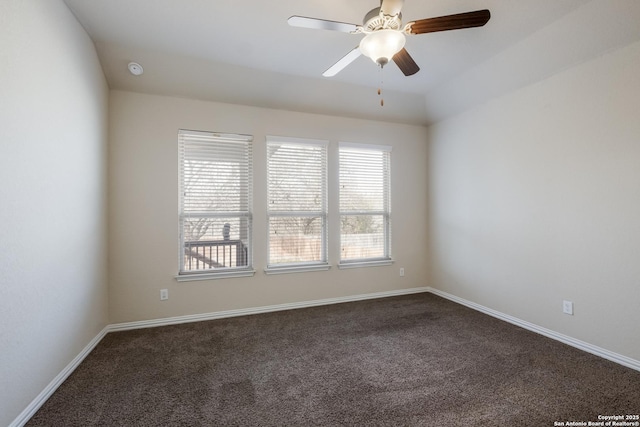 unfurnished room with a ceiling fan, dark carpet, and baseboards