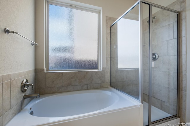 full bathroom featuring a garden tub, plenty of natural light, and a shower stall