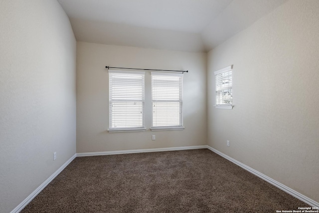 empty room featuring baseboards and dark carpet