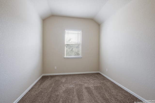 unfurnished room with carpet, baseboards, and vaulted ceiling