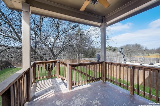 wooden terrace with a ceiling fan, a fenced backyard, and a lawn