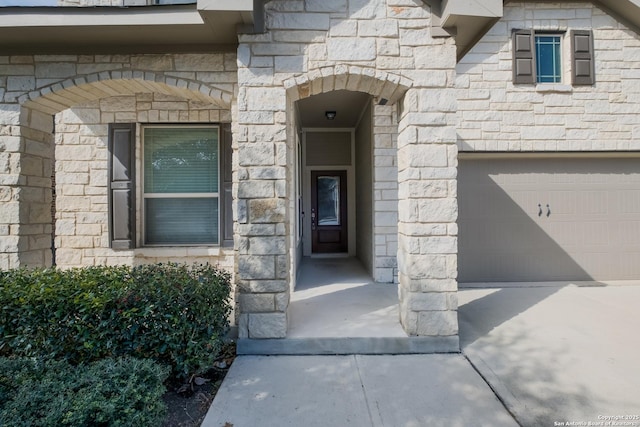 property entrance with a garage and stone siding