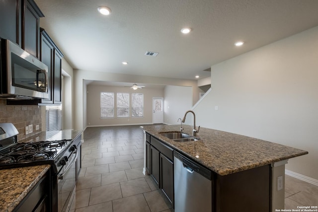 kitchen featuring visible vents, backsplash, appliances with stainless steel finishes, a kitchen island with sink, and a sink