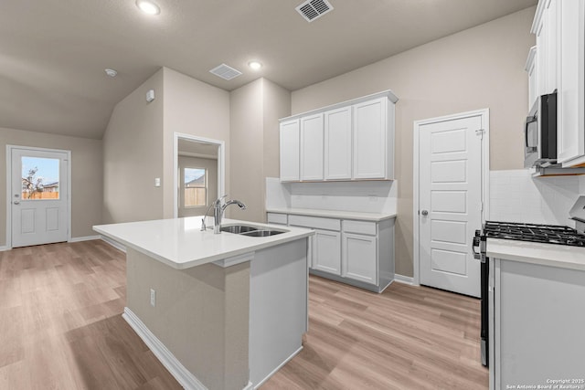 8421 Roadrunner Psge, San Antonio, TX 78222 - kitchen with appliances with stainless steel finishes, a sink, decorative backsplash, light wood-type flooring, and white cabinetry