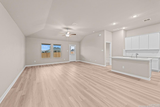 8421 Roadrunner Psge, San Antonio, TX 78222 - unfurnished living room featuring ceiling fan, light wood-style flooring, lofted ceiling, a sink, and baseboards