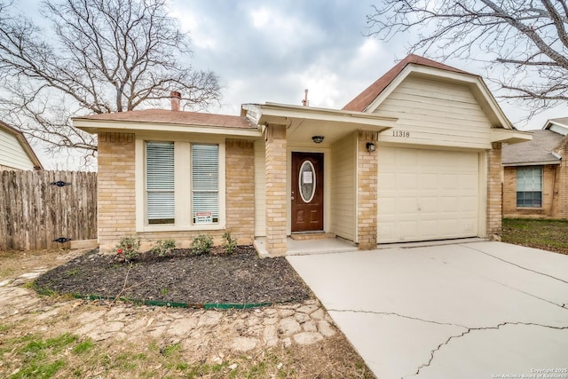 single story home featuring concrete driveway, brick siding, fence, and an attached garage