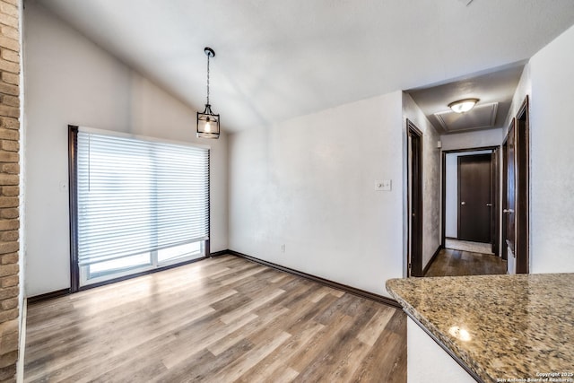 unfurnished dining area with lofted ceiling, baseboards, and wood finished floors