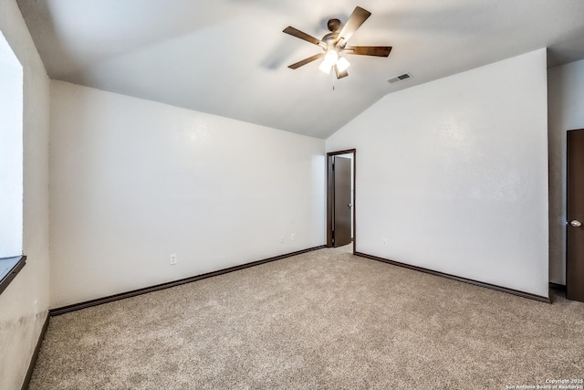 spare room featuring visible vents, baseboards, light colored carpet, ceiling fan, and vaulted ceiling