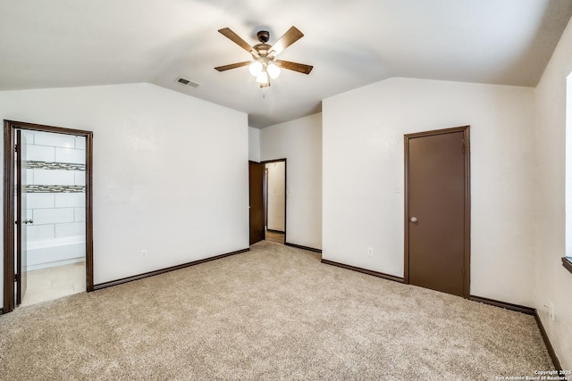 unfurnished bedroom with light colored carpet, visible vents, vaulted ceiling, and baseboards