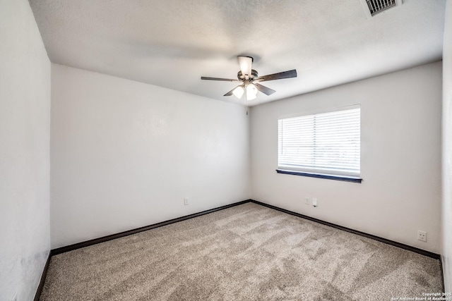 spare room featuring visible vents, light colored carpet, a ceiling fan, a textured ceiling, and baseboards