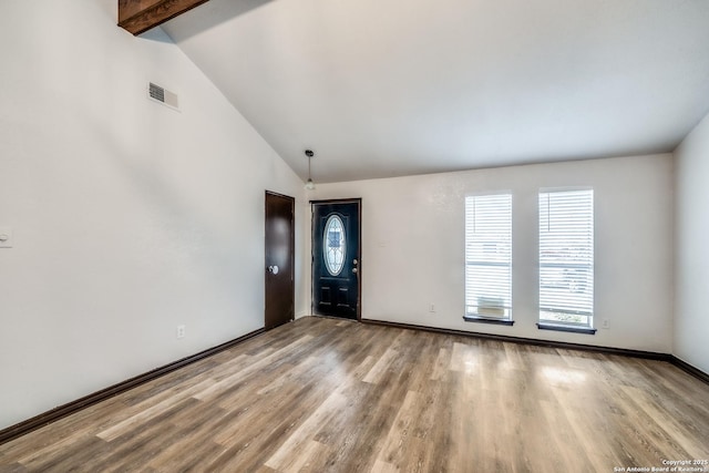 empty room featuring beam ceiling, visible vents, light wood-style flooring, high vaulted ceiling, and baseboards