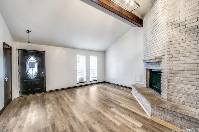 entryway with high vaulted ceiling, a fireplace, wood finished floors, baseboards, and beam ceiling