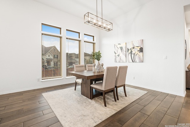 dining room featuring dark wood-style floors, a towering ceiling, and baseboards