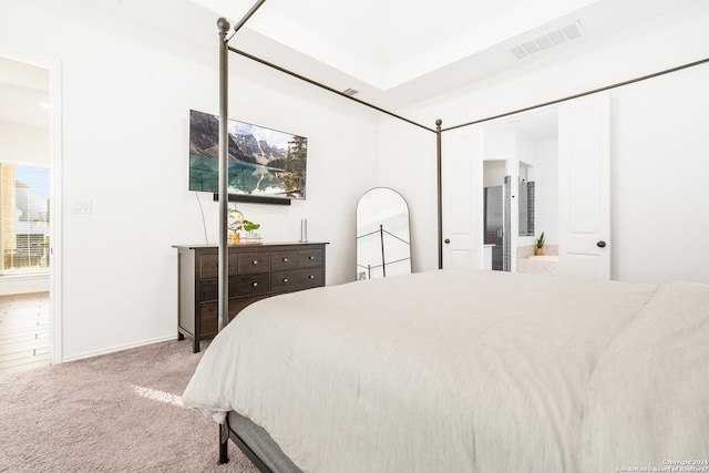 carpeted bedroom with ensuite bath and visible vents