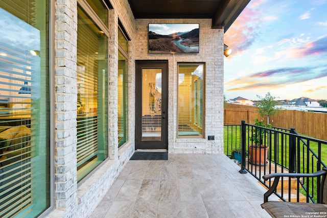 view of exterior entry with brick siding and fence