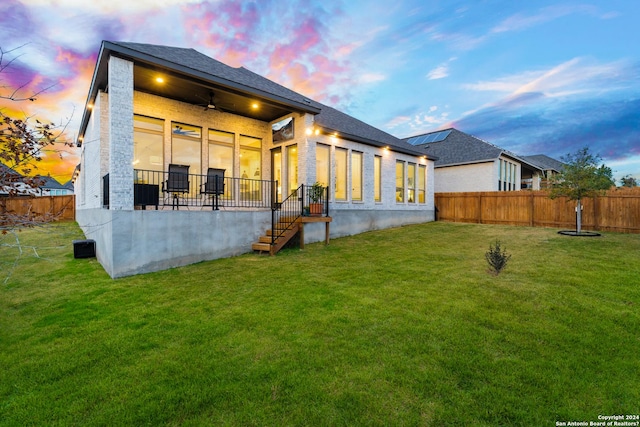 rear view of property with a fenced backyard, a lawn, and a ceiling fan