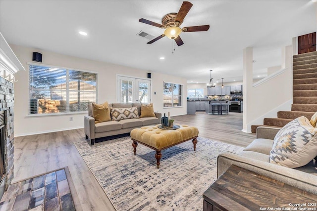 living area with stairway, a fireplace, visible vents, and wood finished floors