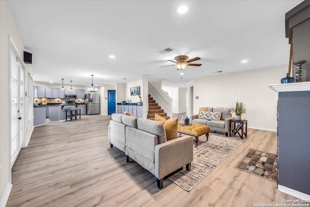 living room featuring light wood-style floors, recessed lighting, visible vents, and stairway