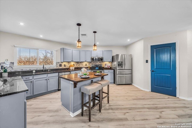 kitchen with visible vents, decorative backsplash, appliances with stainless steel finishes, hanging light fixtures, and a sink