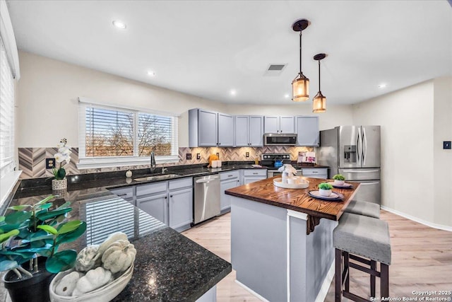 kitchen featuring a sink, visible vents, hanging light fixtures, appliances with stainless steel finishes, and a center island