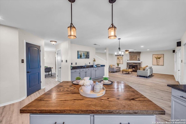 dining room featuring baseboards, light wood-type flooring, a fireplace, and recessed lighting