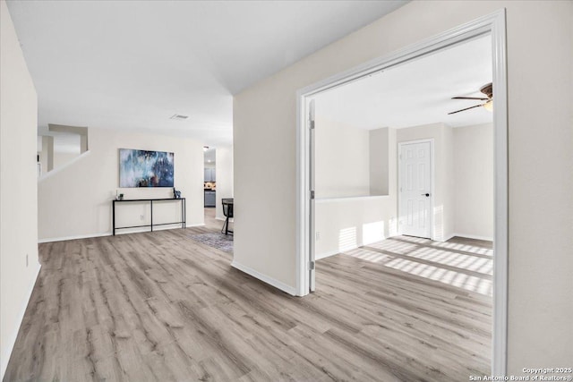 empty room featuring light wood-type flooring, ceiling fan, and baseboards