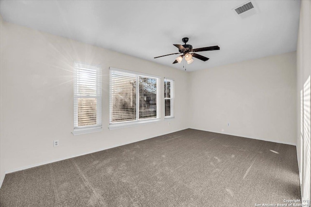 spare room with carpet, visible vents, and a ceiling fan