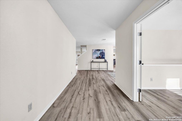 hall with light wood-style flooring and baseboards