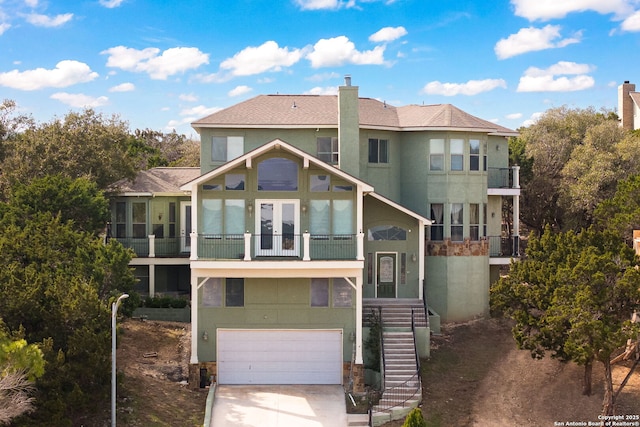 exterior space with a garage, driveway, a chimney, and stucco siding