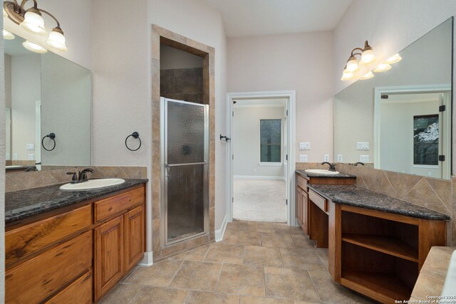 full bath with a stall shower, two vanities, and a sink