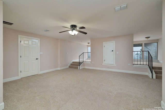 unfurnished living room with light carpet, visible vents, stairway, and ceiling fan