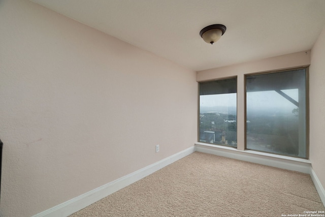 carpeted spare room featuring baseboards