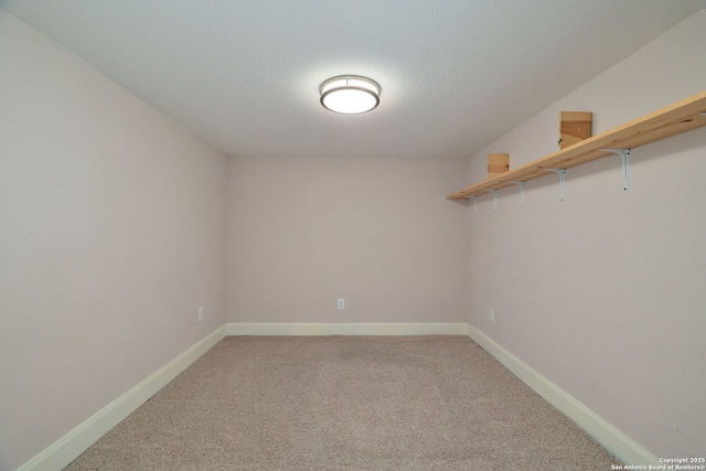 empty room with a textured ceiling, carpet floors, and baseboards