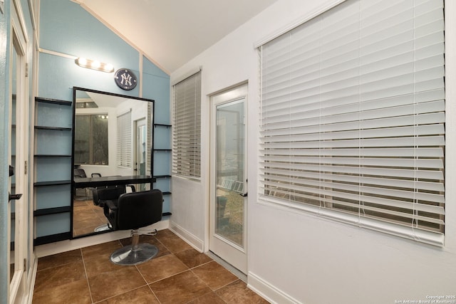 office area with vaulted ceiling and dark tile patterned floors